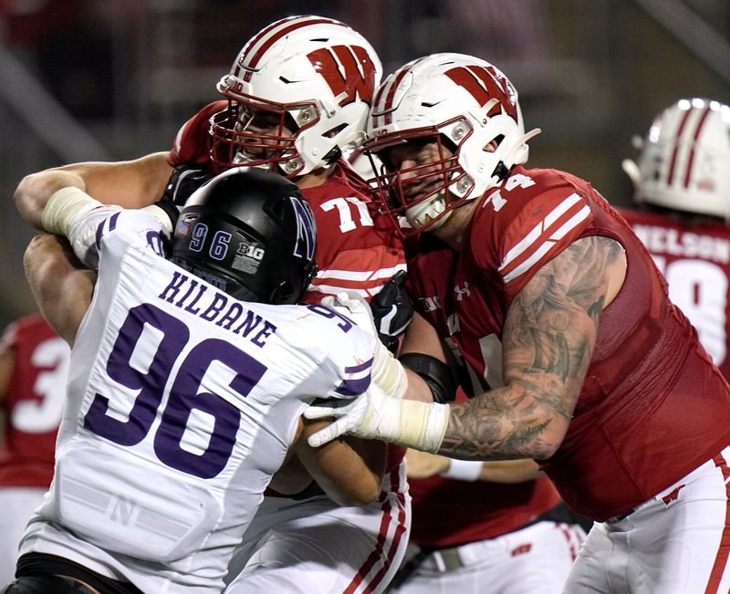 Nov 11, 2023; Madison, Wisconsin, USA; Wisconsin offensive linemen Riley Mahlman (71) and Michael Furtney (74) block Northwestern defensive lineman Michael Kilbane (96) during the fourth quarter at Camp Randall Stadium. Mandatory Credit: Mark Hoffman-USA TODAY Sports