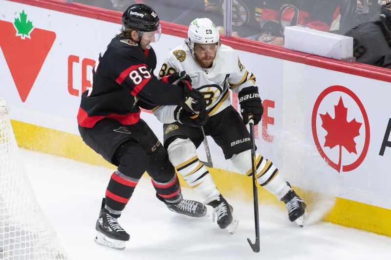 Jan 25, 2024; Ottawa, Ontario, CAN; Ottawa Senators defenseman Jake Sanderson (85) battles with Boston Bruins right wing David Pastrnak (88) in the third period at the Canadian Tire Centre. Mandatory Credit: Marc DesRosiers-USA TODAY Sports