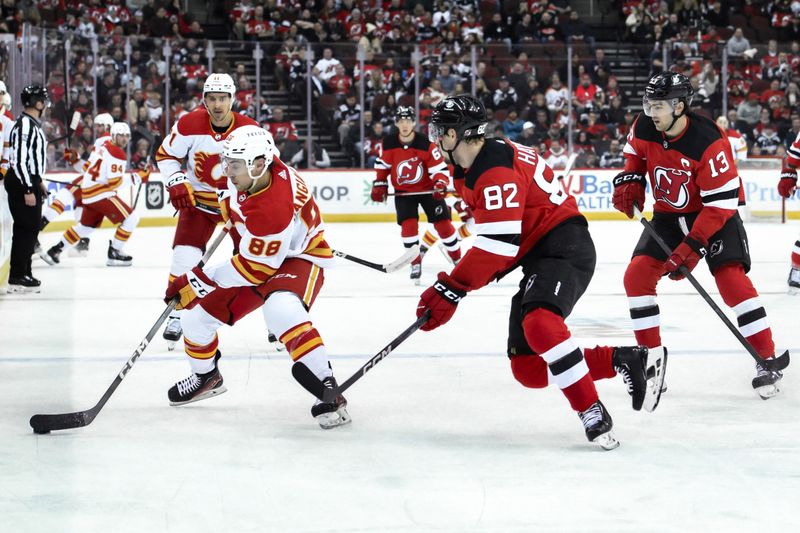 Feb 8, 2024; Newark, New Jersey, USA; Calgary Flames left wing Andrew Mangiapane (88) skates with the puck while being defended by New Jersey Devils defenseman Santeri Hatakka (82) and New Jersey Devils center Nico Hischier (13) during the first period at Prudential Center. Mandatory Credit: John Jones-USA TODAY Sports