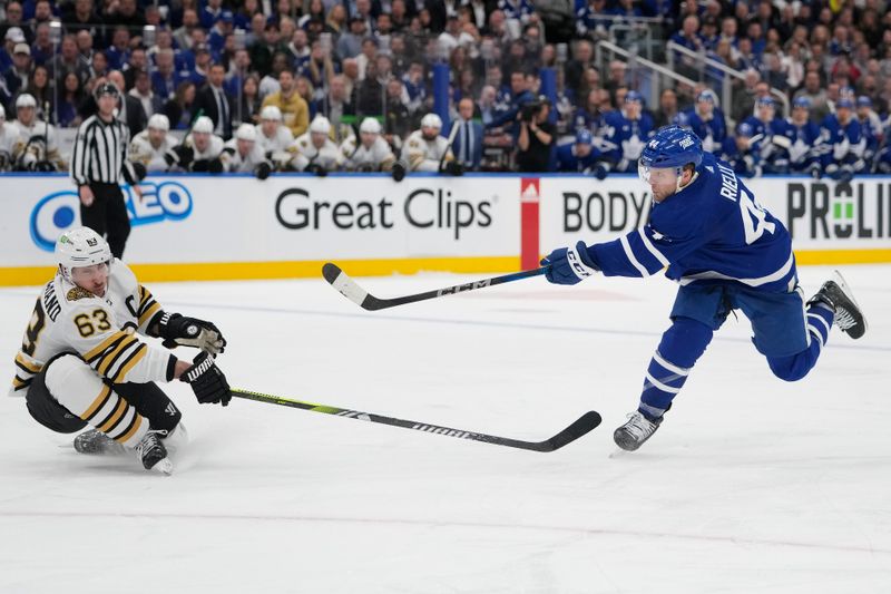 Apr 24, 2024; Toronto, Ontario, CAN; Boston Bruins forward Brad Marchand (63) tries to block a shot by Toronto Maple Leafs defenseman Morgan Rielly (44) during the third period of game three of the first round of the 2024 Stanley Cup Playoffs at Scotiabank Arena. Mandatory Credit: John E. Sokolowski-USA TODAY Sports