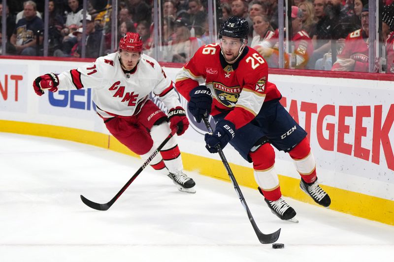 Nov 10, 2023; Sunrise, Florida, USA; Florida Panthers defenseman Uvis Balinskis (26) skates with the puck away from Carolina Hurricanes right wing Jesper Fast (71) during the first period at Amerant Bank Arena. Mandatory Credit: Jasen Vinlove-USA TODAY Sports