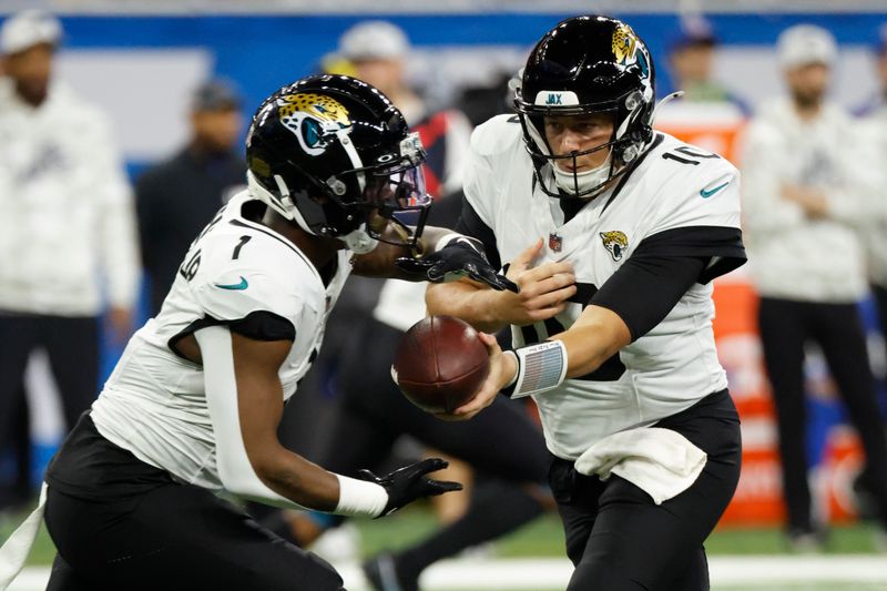 Jacksonville Jaguars quarterback Mac Jones (10) hands off to running back Travis Etienne Jr. (1) Against the Detroit Lions during an NFL football game in Detroit, Sunday, Nov. 17, 2024. (AP Photo/Rick Osentoski)