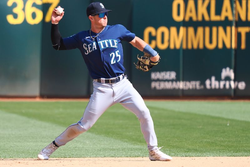 Sep 20, 2023; Oakland, California, USA; Seattle Mariners second baseman Dylan Moore (25) throws the ball to first base against the Oakland Athletics during the eighth inning at Oakland-Alameda County Coliseum. Mandatory Credit: Kelley L Cox-USA TODAY Sports