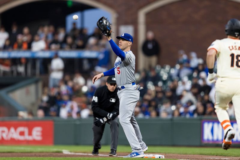 May 15, 2024; San Francisco, California, USA; Los Angeles Dodgers first baseman Freddie Freeman (5) makes the catch for an out against San Francisco Giants catcher Curt Casali (18) during the fifth inning at Oracle Park. Mandatory Credit: John Hefti-USA TODAY Sports