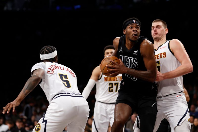 NEW YORK, NEW YORK - DECEMBER 22: Day'Ron Sharpe #20 of the Brooklyn Nets goes to the basket as Kentavious Caldwell-Pope #5 and Nikola Jokic #15 of the Denver Nuggets defend during the first half at Barclays Center on December 22, 2023 in the Brooklyn borough of New York City. NOTE TO USER: User expressly acknowledges and agrees that, by downloading and/or using this Photograph, user is consenting to the terms and conditions of the Getty Images License Agreement. (Photo by Sarah Stier/Getty Images)