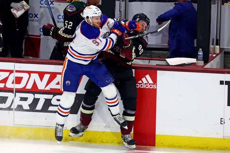 Apr 17, 2024; Tempe, Arizona, USA;  Edmonton Oilers center Connor McDavid (97) checks Arizona Coyotes defenseman J.J. Moser (90) during the second period at Mullett Arena. Mandatory Credit: Mark J. Rebilas-USA TODAY Sports