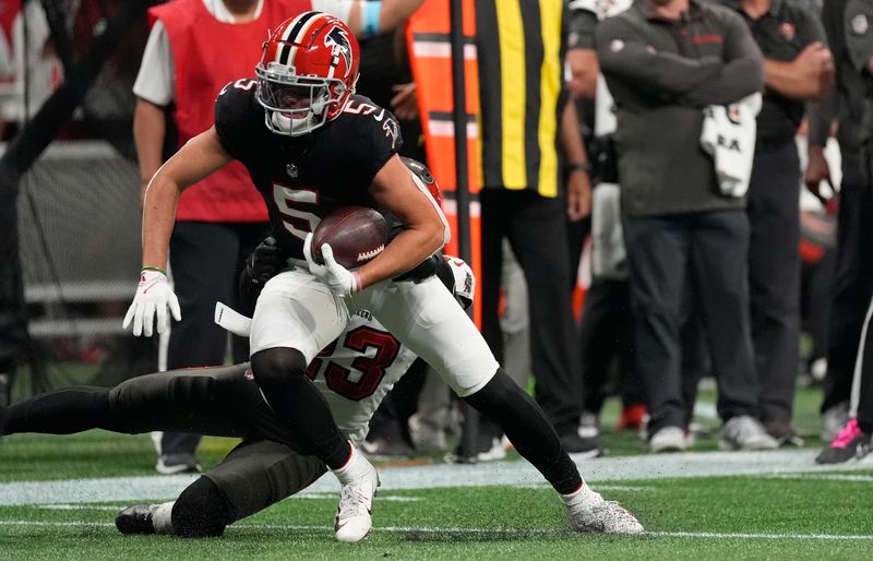 Atlanta Falcons wide receiver Drake London (5) slips a tackle by Tampa Bay Buccaneers safety Tykee Smith (23) during the first half of an NFL football game Thursday, Oct. 3, 2024, in Atlanta. (AP Photo/John Bazemore)