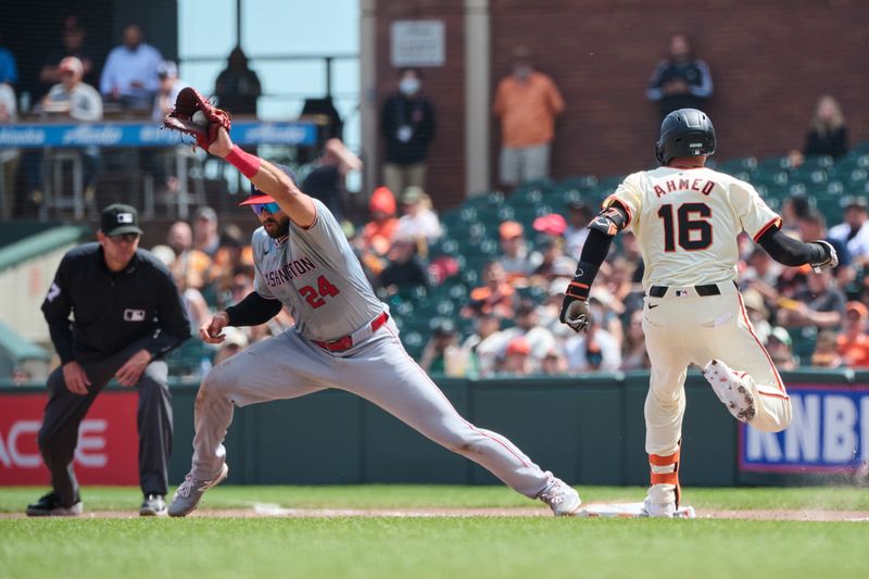 Apr 10, 2024; San Francisco, California, USA; San Francisco Giants shortstop Nick Ahmed (16) touches first base with a single ahead of the catch by Washington Nationals first baseman Joey Gallo (24) during the fifth inning at Oracle Park. Mandatory Credit: Robert Edwards-USA TODAY Sports