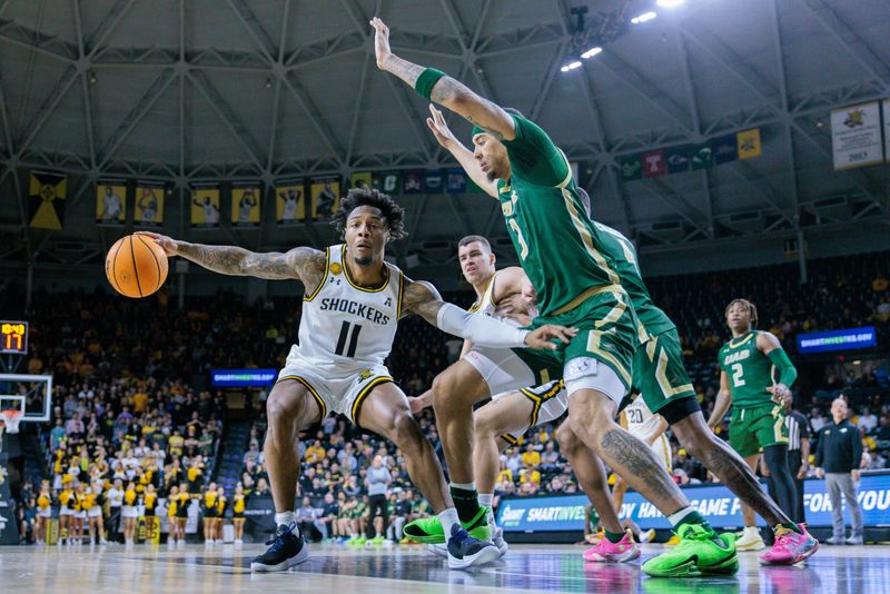 Feb 27, 2025; Wichita, Kansas, USA; Wichita State Shockers guard Justin Hill (11) drives to the basket around UAB Blazers forward Yaxel Lendeborg (3) during the second half at Charles Koch Arena. Mandatory Credit: William Purnell-Imagn Images