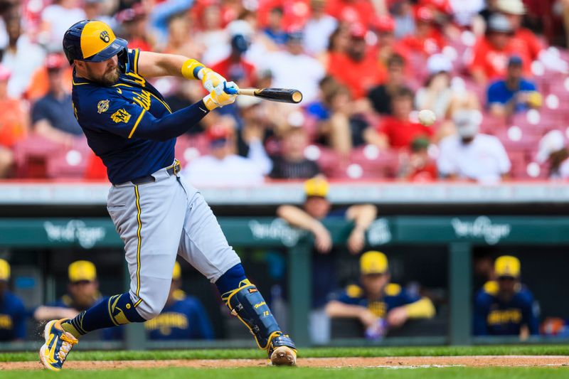 Jun 4, 2025; Cincinnati, Ohio, USA; Milwaukee Brewers first baseman Rhys Hoskins (12) hits a single in the fourth inning against the Cincinnati Reds at Great American Ball Park. Mandatory Credit: Katie Stratman-Imagn Images
