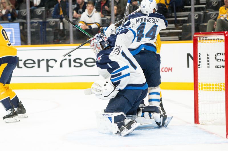 Nov 23, 2024; Nashville, Tennessee, USA;  Winnipeg Jets goaltender Eric Comrie (1) blocks a shot against the Nashville Predators during the first period at Bridgestone Arena. Mandatory Credit: Steve Roberts-Imagn Images