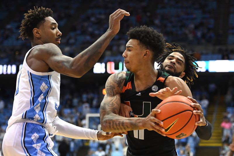 Feb 13, 2023; Chapel Hill, North Carolina, USA; Miami (Fl) Hurricanes guard Jordan Miller (11) with the ball as North Carolina Tar Heels forward Leaky Black (1) and guard R.J. Davis (4) pressure in the second half at Dean E. Smith Center. Mandatory Credit: Bob Donnan-USA TODAY Sports