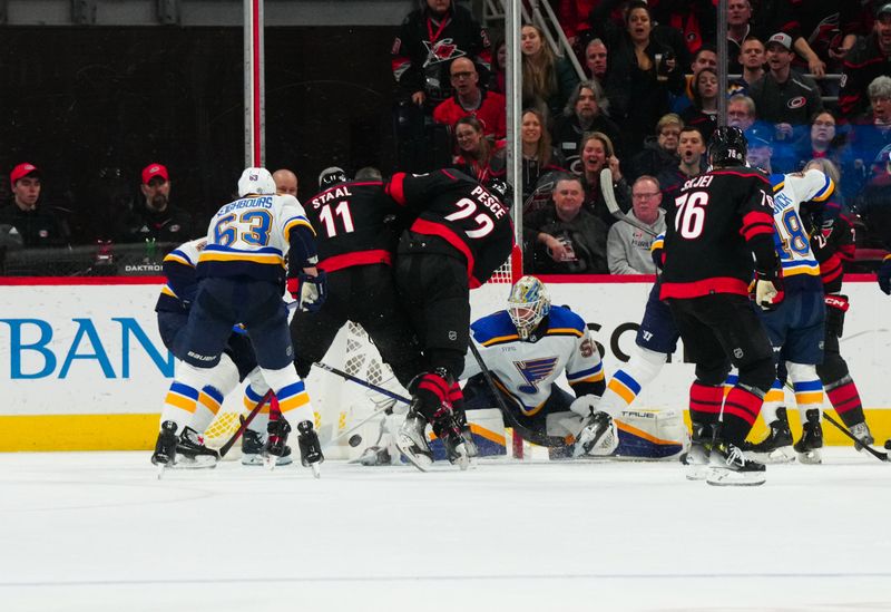 Jan 6, 2024; Raleigh, North Carolina, USA; St. Louis Blues goaltender Jordan Binnington (50) stoops the shot against Carolina Hurricanes defenseman Brett Pesce (22) and center Jordan Staal (11) during the second period at PNC Arena. Mandatory Credit: James Guillory-USA TODAY Sports