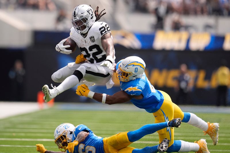 Las Vegas Raiders running back Alexander Mattison (22) runs against Los Angeles Chargers linebacker Daiyan Henley (0) and cornerback Asante Samuel Jr. (26) during the first half of an NFL football game, Sunday, Sept. 8, 2024, in Inglewood, Calif. (AP Photo/Marcio Jose Sanchez)