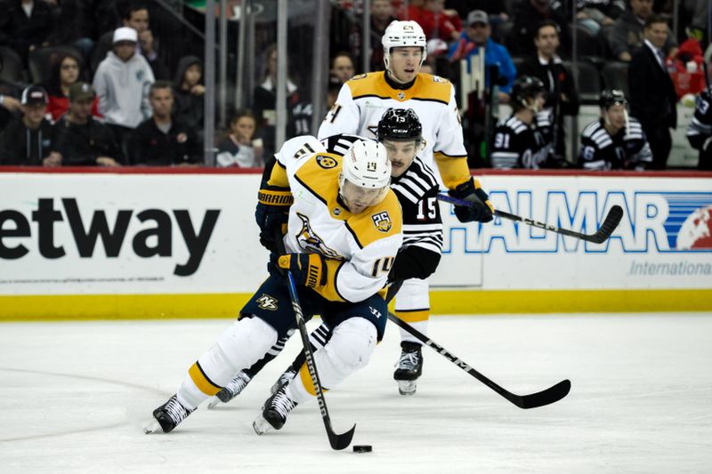 Apr 7, 2024; Newark, New Jersey, USA; Nashville Predators center Gustav Nyquist (14) skates with the puck while being defended by New Jersey Devils center Shane Bowers (15) during the second period at Prudential Center. Mandatory Credit: John Jones-USA TODAY Sports