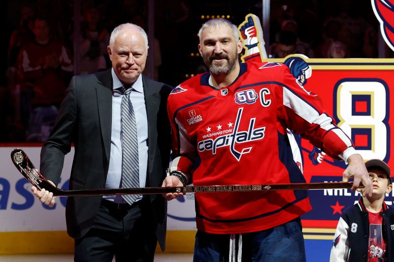 Apr 10, 2025; Washington, District of Columbia, USA; Washington Capitals president of hockey operations Brian McClellan (L) presents Capitals left wing Alex Ovechkin (8) with a gold stick honoring his becoming the NHL all-time goals leader prior to the Capitals' game against the Carolina Hurricanes at Capital One Arena. Mandatory Credit: Geoff Burke-Imagn Images