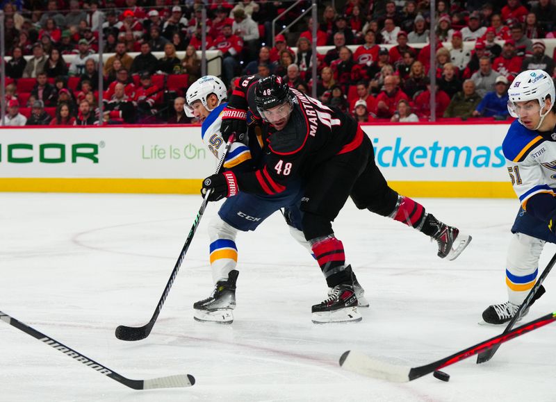 Jan 6, 2024; Raleigh, North Carolina, USA; Carolina Hurricanes left wing Jordan Martinook (48) loses the puck against St. Louis Blues center Jordan Kyrou (25) during the first period at PNC Arena. Mandatory Credit: James Guillory-USA TODAY Sports