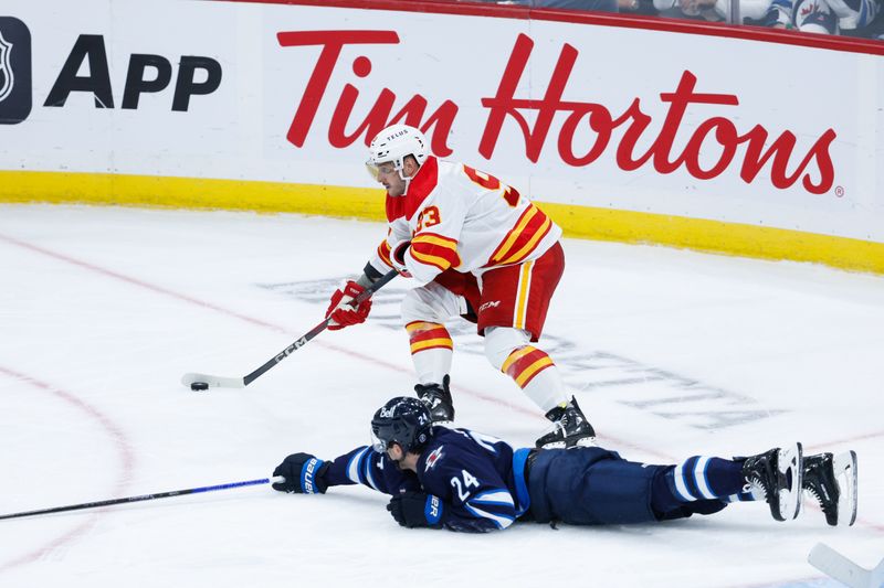 Oct 2, 2024; Winnipeg, Manitoba, CAN;  Calgary Flames forward Martin Frk (93) skates around Winnipeg Jets defenseman Hayden Fleury (24) during the third period at Canada Life Centre. Mandatory Credit: Terrence Lee-Imagn Images