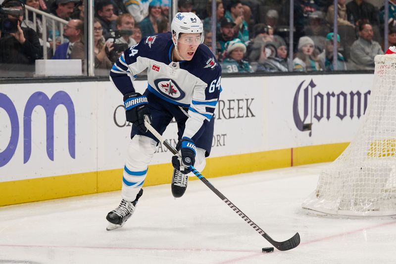 Dec 12, 2023; San Jose, California, USA; Winnipeg Jets defenseman Logan Stanley (64) skates with the puck against the San Jose Sharks during the second period at SAP Center at San Jose. Mandatory Credit: Robert Edwards-USA TODAY Sports