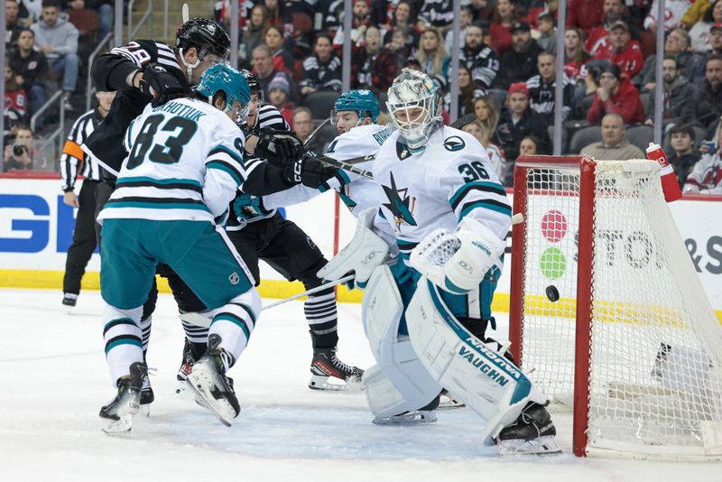 Dec 1, 2023; Newark, New Jersey, USA; New Jersey Devils center Dawson Mercer (91) scores a goal past San Jose Sharks goaltender Kaapo Kahkonen (36) as defenseman Nikita Okhotiuk (83) defends during the first period at Prudential Center. Mandatory Credit: Vincent Carchietta-USA TODAY Sports