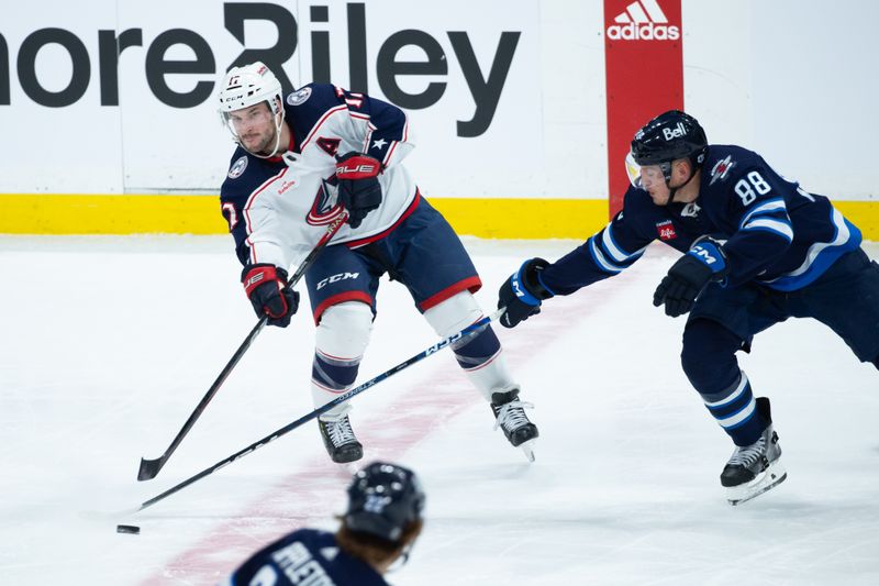 Jan 9, 2024; Winnipeg, Manitoba, CAN; Columbus Blue Jackets forward Justin Danforth (17) passes the puck past Winnipeg Jets defenseman Nate Schmidt (88) during the third period at Canada Life Centre. Mandatory Credit: Terrence Lee-USA TODAY Sports