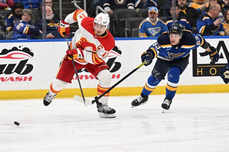 Jan 16, 2025; St. Louis, Missouri, USA; St. Louis Blues left wing Jake Neighbours (63) pressures Calgary Flames center Mikael Backlund (11) in the third period at Enterprise Center. Mandatory Credit: Joe Puetz-Imagn Images
