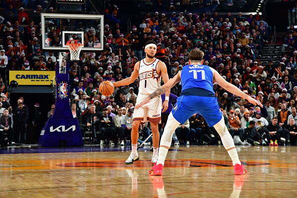 PHOENIX, AZ - DECEMBER 25: Devin Booker #1 of the Phoenix Suns handles the ball against defender Luka Doncic #77 of the Dallas Mavericks during the game on December 25, 2023 at Footprint Center in Phoenix, Arizona. NOTE TO USER: User expressly acknowledges and agrees that, by downloading and or using this photograph, user is consenting to the terms and conditions of the Getty Images License Agreement. Mandatory Copyright Notice: Copyright 2023 NBAE (Photo by Kate Frese/NBAE via Getty Images)