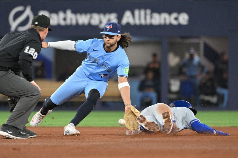 Apr 30, 2024; Toronto, Ontario, CAN;   Toronto Blue Jays shortstop Bo Bichette (11) takes the throw from the plate before tagging out Kansas City Royals shortstop Bobby Witt Jr. (7) on an attempted steal in the sixth inning at Rogers Centre. Mandatory Credit: Dan Hamilton-USA TODAY Sports