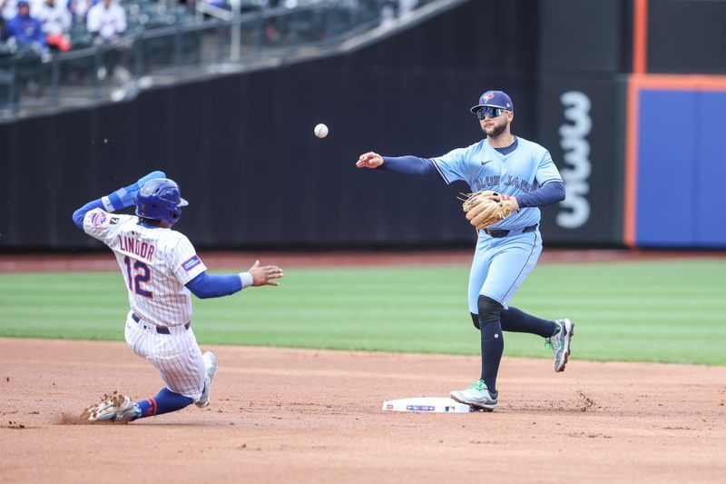 Apr 6, 2025; New York City, New York, USA;  Toronto Blue Jays shortstop Bo Bichette (11) throws past New York Mets shortstop Francisco Lindor (12) to complete a double play in the first inning at Citi Field. Mandatory Credit: Wendell Cruz-Imagn Images