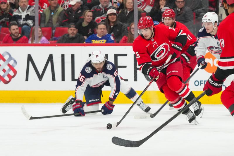 Dec 9, 2025; Raleigh, North Carolina, USA;  Carolina Hurricanes defenseman Sean Walker (26) skates with the puck past Columbus Blue Jackets right wing Kirill Marchenko (86) during the second period at Lenovo Center. Mandatory Credit: James Guillory-Imagn Images