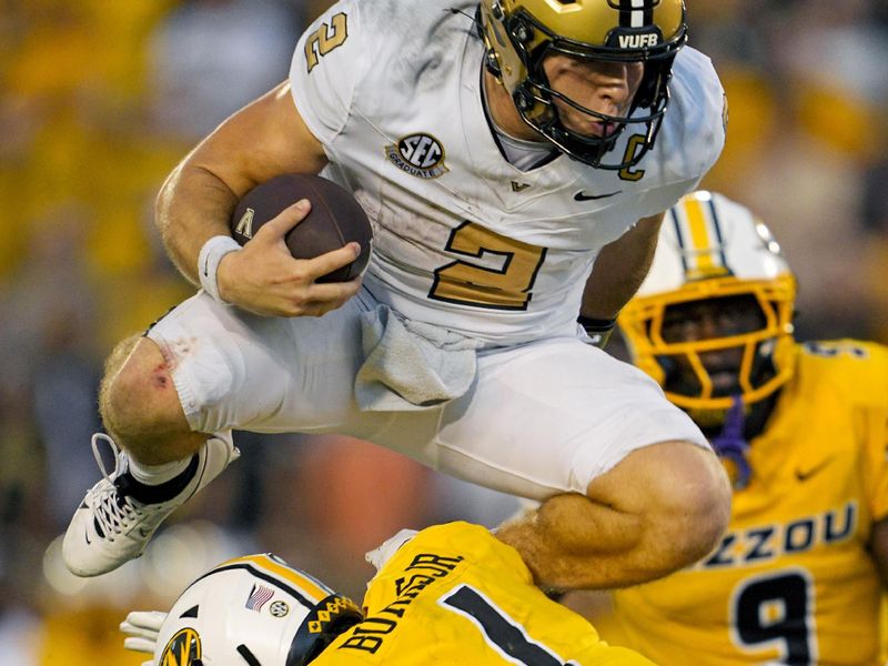 Sep 21, 2024; Columbia, Missouri, USA; Vanderbilt Commodores quarterback Diego Pavia (2) leaps over Missouri Tigers safety Marvin Burks Jr. (1) during overtime at Faurot Field at Memorial Stadium. Mandatory Credit: Jay Biggerstaff-Imagn Images