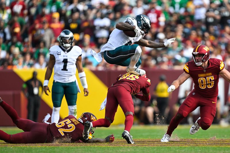 Philadelphia Eagles running back D'Andre Swift runs the ball and hurdles Washington Commanders safety Percy Butler during the second half of an NFL football game, Sunday, Oct. 29, 2023, in Landover, Md. (AP Photo/Terrance Williams)