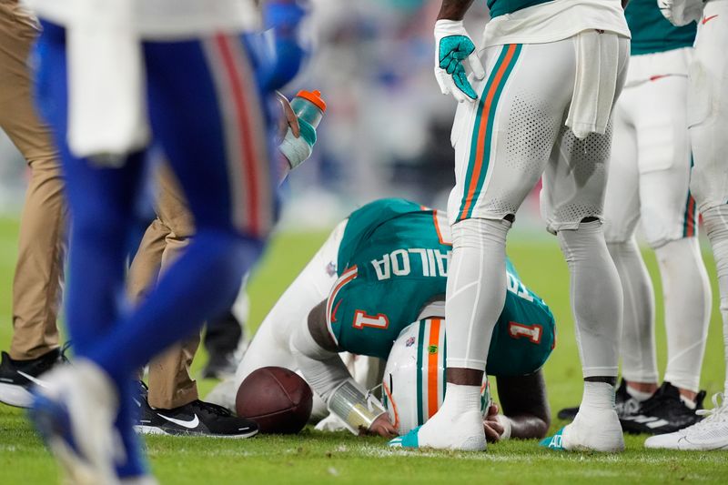 Miami Dolphins quarterback Tua Tagovailoa (1) is assisted on the field during the second half of an NFL football game against the Buffalo Bills, Thursday, Sept. 12, 2024, in Miami Gardens, Fla. (AP Photo/Rebecca Blackwell)