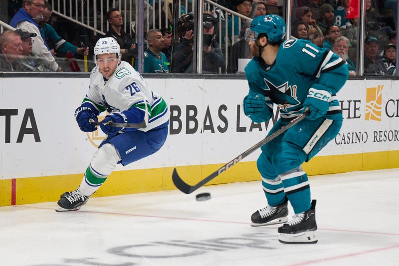 Nov 2, 2024; San Jose, California, USA; Vancouver Canucks defenseman Erik Brannstrom (26) plays the puck against San Jose Sharks center Luke Kunin (11) during the second period at SAP Center at San Jose. Mandatory Credit: Robert Edwards-Imagn Images