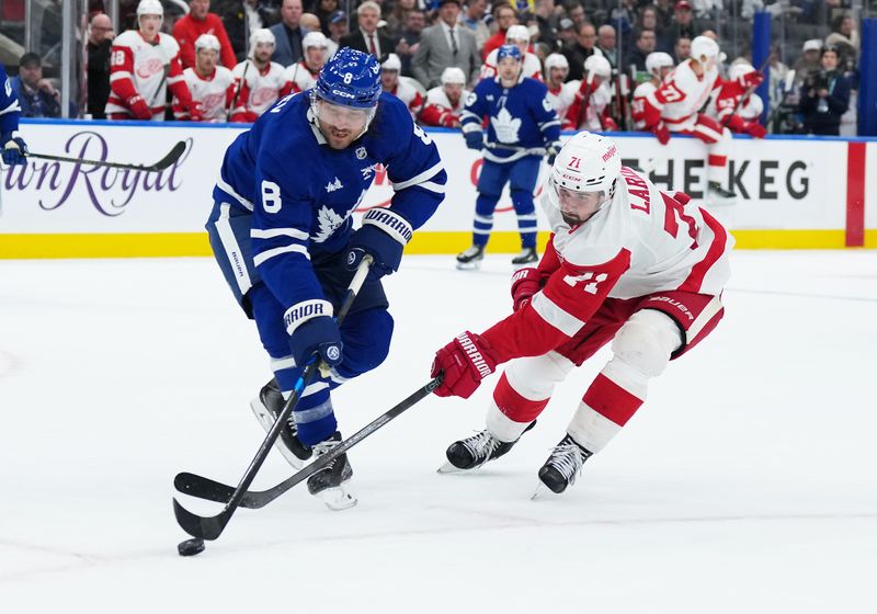 Oct 2, 2025; Toronto, Ontario, CAN; Detroit Red Wings center Dylan Larkin (71) battles for the puck with Toronto Maple Leafs defenseman Chris Tanev (8) during the second period at Scotiabank Arena. Mandatory Credit: Nick Turchiaro-Imagn Images