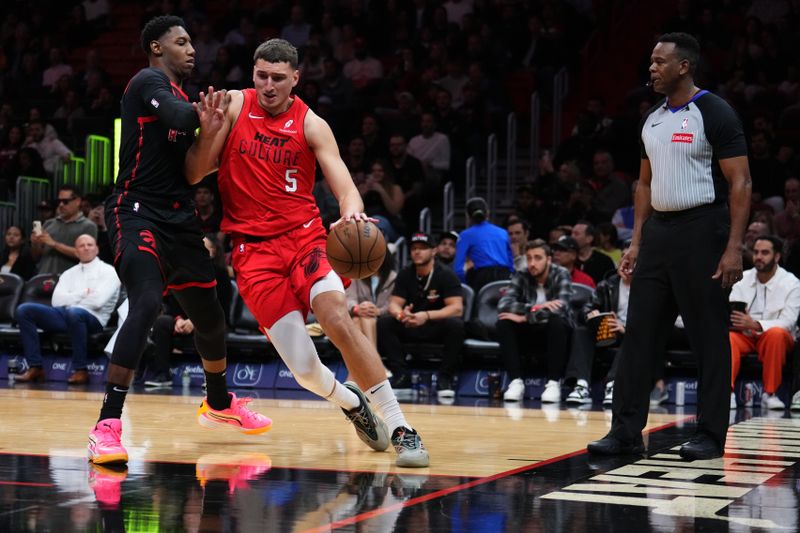 MIAMI, FLORIDA - DECEMBER 12: Nikola Jovic #5 of the Miami Heat dribbles the ball against RJ Barrett #9 of the Toronto Raptors during the second quarter at Kaseya Center on December 12, 2024 in Miami, Florida. NOTE TO USER: User expressly acknowledges and agrees that, by downloading and or using this Photograph, user is consenting to the terms and conditions of the Getty Images License Agreement. (Photo by Rich Storry/Getty Images)