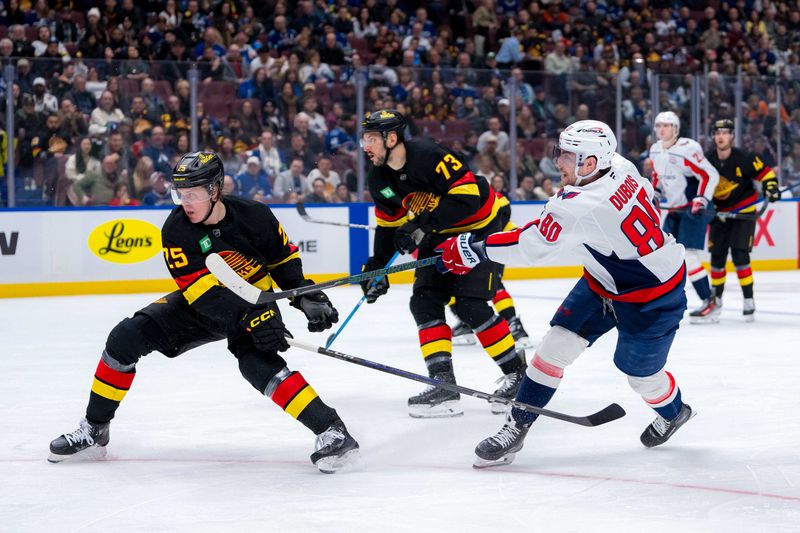 Jan 25, 2025; Vancouver, British Columbia, CAN; Vancouver Canucks defenseman Vincent Desharnais (73) watches as Washington Capitals forward Pierre-Luc Dubois (80) shoots around defenseman Elias Pettersson (25) in the third period at Rogers Arena. Mandatory Credit: Bob Frid-Imagn Images