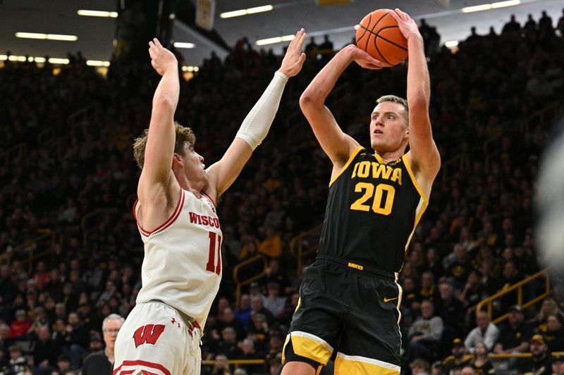 Feb 17, 2024; Iowa City, Iowa, USA; Iowa Hawkeyes forward Payton Sandfort (20) shoots the ball as Wisconsin Badgers guard Max Klesmit (11) defends during the second half at Carver-Hawkeye Arena. Mandatory Credit: Jeffrey Becker-USA TODAY Sports