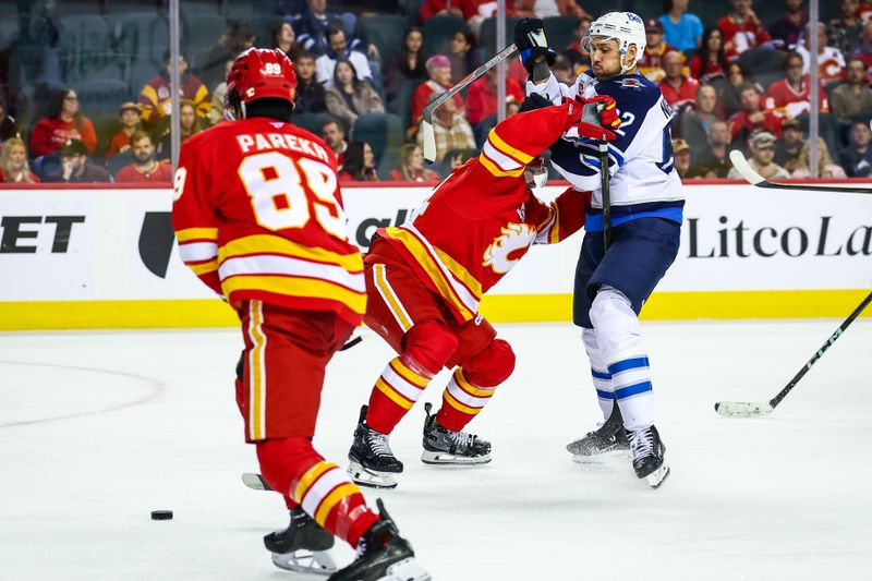 Oct 3, 2025; Calgary, Alberta, CAN; Calgary Flames defenseman Jake Bean (24) and Winnipeg Jets right wing Nino Niederreiter (62) battles for the puck during the third period at Scotiabank Saddledome. Mandatory Credit: Sergei Belski-Imagn Images