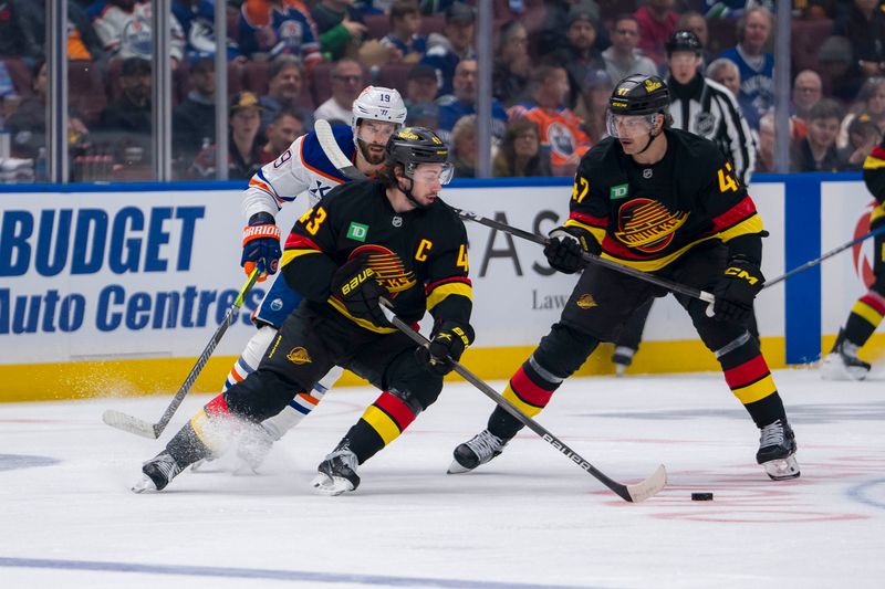 Nov 9, 2024; Vancouver, British Columbia, CAN; Edmonton Oilers forward Adam Henrique (19) and Vancouver Canucks defenseman Noah Juulsen (47) watch defenseman Quinn Hughes (43) handles the puck during the first period at Rogers Arena. Mandatory Credit: Bob Frid-Imagn Images