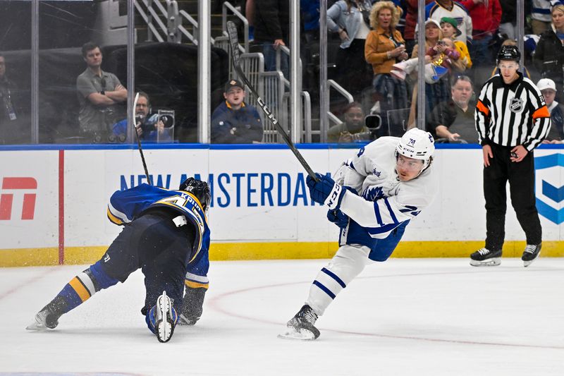 Feb 19, 2024; St. Louis, Missouri, USA;  Toronto Maple Leafs center Bobby McMann (74) shoots and scores and empty net goal against St. Louis Blues defenseman Torey Krug (47) during the third period at Enterprise Center. Mandatory Credit: Jeff Curry-USA TODAY Sports