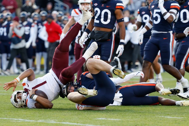 Nov 25, 2023; Charlottesville, Virginia, USA; Virginia Tech Hokies quarterback Kyron Drones (1) is tackled by Virginia Cavaliers linebacker James Jackson (7) during the first quarter at Scott Stadium. Mandatory Credit: Geoff Burke-USA TODAY Sports