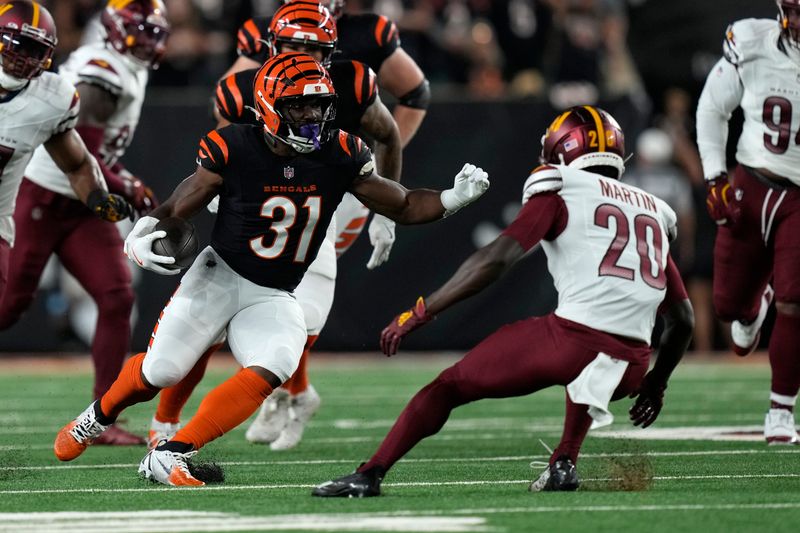 Cincinnati Bengals running back Zack Moss (31) runs from Washington Commanders safety Quan Martin (20) during the first half of an NFL football game, Monday, Sept. 23, 2024, in Cincinnati. (AP Photo/Carolyn Kaster)