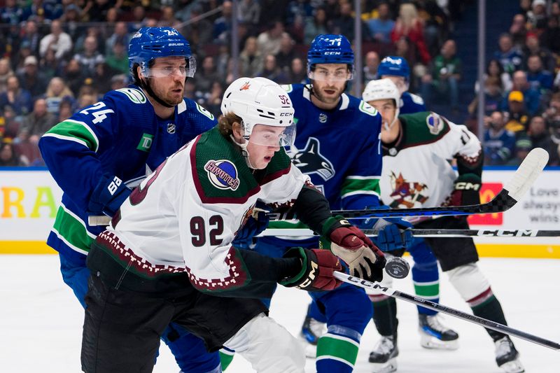 Jan 18, 2024; Vancouver, British Columbia, CAN; Vancouver Canucks forward Pius Suter (24) wathces Arizona Coyotes forward Logan Cooley (92) reach for the flying puck in the first period at Rogers Arena. Mandatory Credit: Bob Frid-USA TODAY Sports