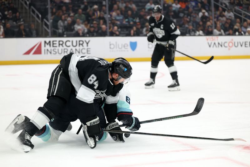 Nov 23, 2024; Los Angeles, California, USA;  Los Angeles Kings defenseman Vladislav Gavrikov (84) and Seattle Kraken defenseman Adam Larsson (6) fight for the puck during the first period at Crypto.com Arena. Mandatory Credit: Kiyoshi Mio-Imagn Images