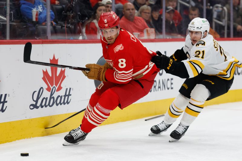 Dec 2, 2025; Detroit, Michigan, USA;  Detroit Red Wings defenseman Ben Chiarot (8) skates with the puck chased by Boston Bruins center Alex Steeves (21) in the first period at Little Caesars Arena. Mandatory Credit: Rick Osentoski-Imagn Images