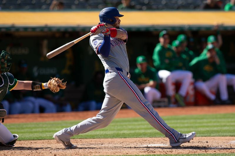 May 8, 2024; Oakland, California, USA; Texas Rangers catcher Jonah Heim (28) follows through on his two-run single against the Oakland Athletics during the first inning at Oakland-Alameda County Coliseum. Mandatory Credit: D. Ross Cameron-USA TODAY Sports