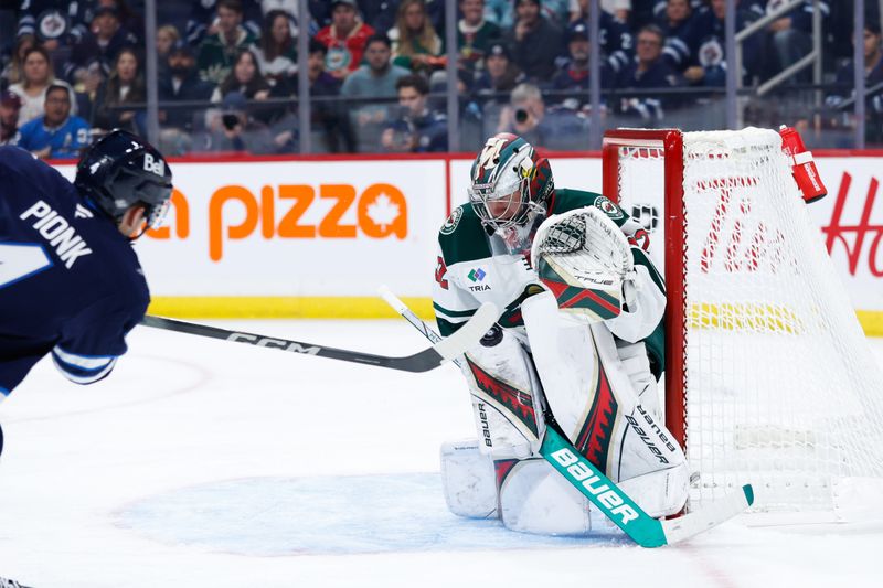 Oct 13, 2024; Winnipeg, Manitoba, CAN;  Minnesota Wild goalie Filip Gustavsson (32) makes a save on a shot by Winnipeg Jets defenseman Neal Pionk (4) during the second period at Canada Life Centre. Mandatory Credit: Terrence Lee-Imagn Images