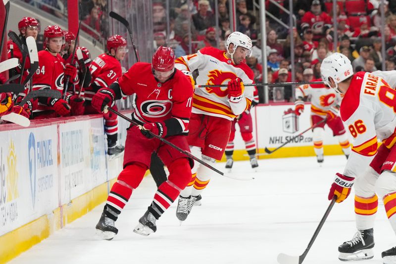 Nov 30, 2025; Raleigh, North Carolina, USA;  Calgary Flames center Nazem Kadri (91) side steps the check by Carolina Hurricanes center Jordan Staal (11) during the second period at Lenovo Center. Mandatory Credit: James Guillory-Imagn Images