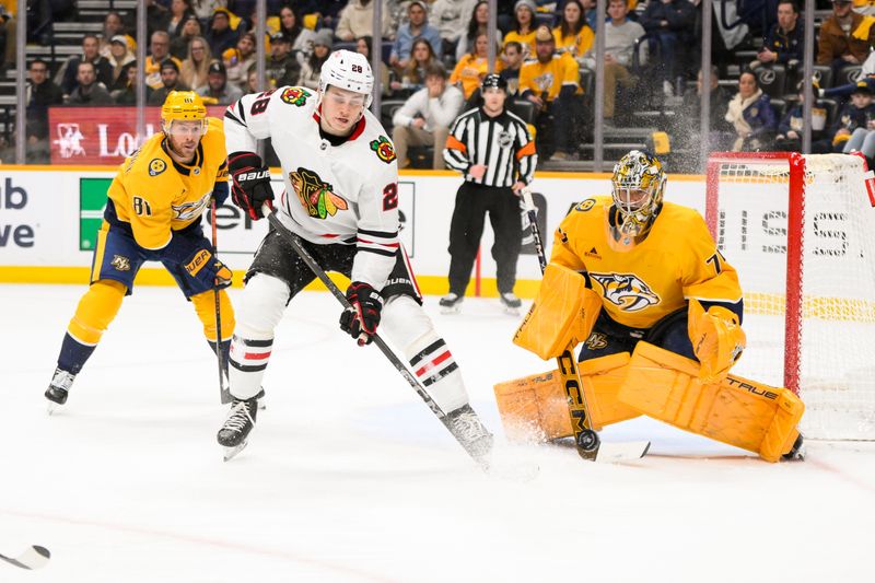 Jan 16, 2025; Nashville, Tennessee, USA;  Nashville Predators goaltender Juuse Saros (74) blocks the deflection of Chicago Blackhawks center Colton Dach (28) during the second period at Bridgestone Arena. Mandatory Credit: Steve Roberts-Imagn Images